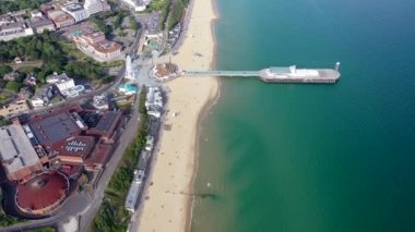 Bournemouth Sahili 'nin, Gözlem Çarkı' nın ve İskelenin insansız hava aracı görüntüleri güneşli bir yaz gününde bir sürü insanın İngiliz Dorset kumlu plajı ve okyanusunda dinlenip güneşlendiği görüntüler.