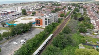 İngiltere 'nin batı Sussex kentindeki bir sahil kasabası ve limanı olan Shoreham-by-Sea kasabasının hava görüntüleri, konut ve iş yerleri boyunca tren rayları üzerinde seyahat eden bir treni gösteriyor.