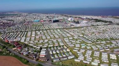 Skegness Ingoldmells 'deki kumsalın hava görüntüleri mavi okyanusta rüzgar türbinleri jeneratörleriyle okyanus kıyısındaki bir karavan kampında kervanları gösteriyor.