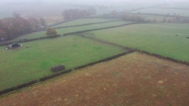 İngiltere 'nin Leeds West Yorkshire kentindeki Wetherby köyünün sisli bir gününde İngiliz kırsalındaki çiftçilerin kışın yukarıdan tarlalarını gösteriyor.