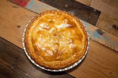 Lezzetli etli bir etli turta, yukarıdan bakınca ahşap mutfak masasının üzerindeki lezzetli etli turtayı ve kabuğu gösteriyor.