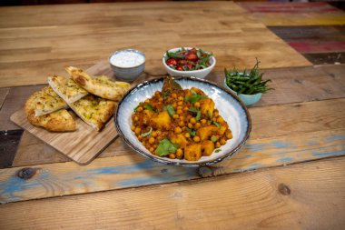 Ahşap mutfak masasında nohut ve patatesten yapılmış bir kase lezzetli Hint yemeği.