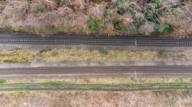 A straight down aerial view of an old train track in the winter and spring time