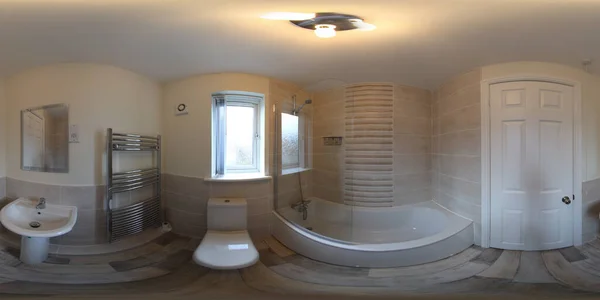 A 360 Degree Full Sphere Panoramic photo of a modern newly built house interior showing a brand new modern bathroom with bath tub, toilet, basin sink and square shower.