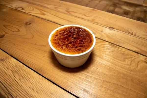 A delicious french desert of Rhubarb and Cardamom Creme Brulee on a wooden kitchen table