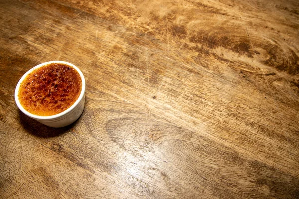 A delicious french desert of Rhubarb and Cardamom Creme Brulee on a wooden kitchen table