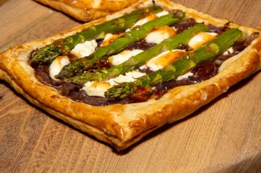 Ahşap mutfak masasında nefis bir kuşkonmaz, karamelize soğan ve keçi peyniri galeti.