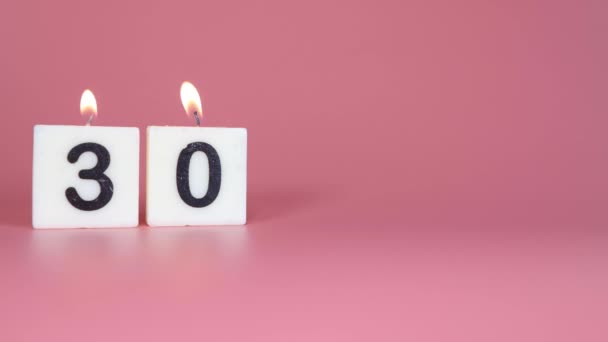 誕生日や記念日を祝うピンクの背景に30番が灯され吹き飛ばされるという正方形のろうそく — ストック動画