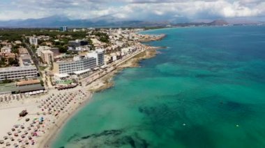 Aerial drone footage of the beach front on the Spanish island of Majorca Mallorca, Spain viewed from above on a bright sunny summers day showing the beach front in the village of Can Picafort
