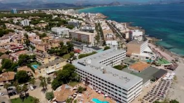 Aerial drone footage of the beach front on the Spanish island of Majorca Mallorca, Spain viewed from above on a bright sunny summers day showing the beach front in the village of Can Picafort