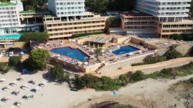 İspanya 'nın İbiza adasının havadan çekilmiş görüntüleri, İspanya' nın Balear Adaları 'nda yaz mevsiminde Cala Llonga' da insanlarla dolu güzel sahil ve otelleri gösteriyor.