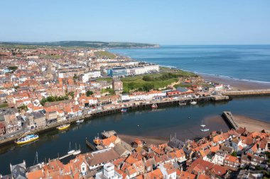 İngiltere 'nin kuzeyindeki Yorkshire kentindeki Whitby kasabasının hava aracı fotoğrafı yazları güneşli bir günde Whitby Jetty ve deniz fenerinin okyanusa açıldığını gösteriyor.