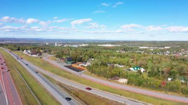 Aerial drone footage of the beautiful town of Truro in central Nova Scotia Canada showing the main highway with the town in the background on a sunny day with a few clouds in the sky