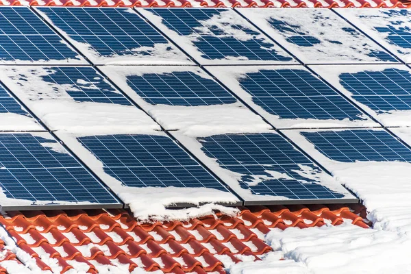 House roof covered with snow, pv solar panels in winter. Electricity from the sun - photovoltaic solar panels under the snow during winter.