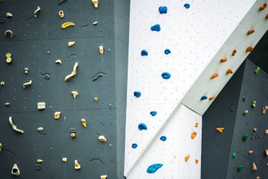 Tırmanma duvarının soyut renginde ayak parmağı ve el ele tutuşan çiviler açık hava spor salonu macera parkında çeşitli renkli tutamaklar..