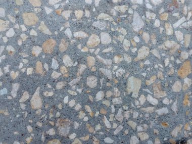 Kumlu beton yüzey ve küçük taşlar.