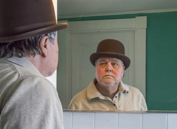 Senior man wearing a brown derby in the bathroom mirror — Stock Photo, Image