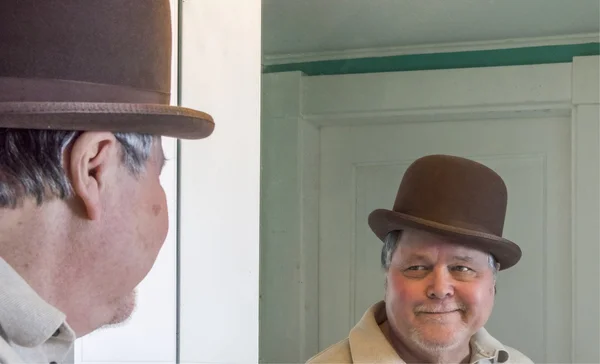 Senior man wearing a derby in bathroom mirror Stock Image