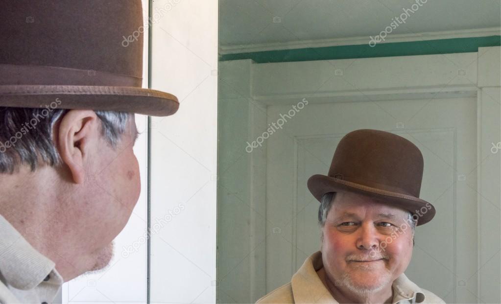 Senior man wearing a derby in bathroom mirror