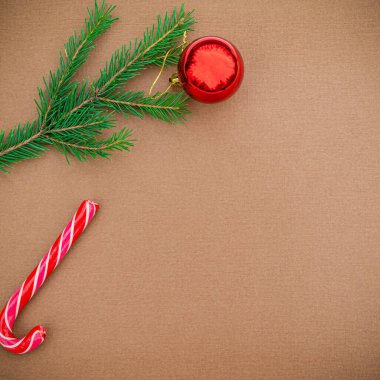Noel ya da yeni yıl geçmişi. Kırmızı top, lolipop, ladin dalı kahverengi arka planda. Düz konum, metin için boş boşluk.