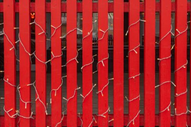 Kırmızı çitlerin ampullerle süslenmesi. Noel ve Yeni Yıl kavramı.