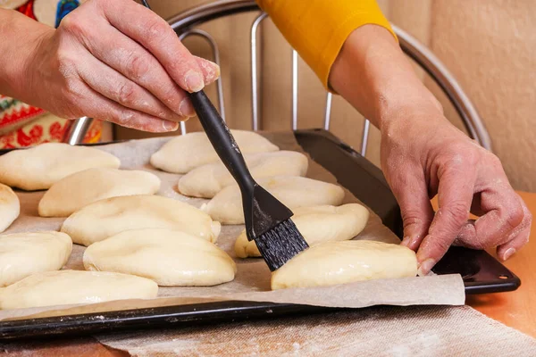 Bir kadın çiğ Rus turtalarının üzerine yumurtayı dolduruyor. Ev yapımı pişirme..