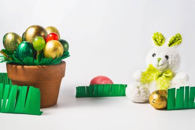 Yumurtalı ve şekerli Paskalya çömleği. Çok renkli yumurtalar çimenlerin içinde gizlidir. Paskalya tatili konsepti.