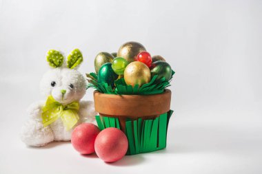 Bir tencere renkli yumurta, şeker ve oyuncak tavşan. Paskalya tatili konsepti.