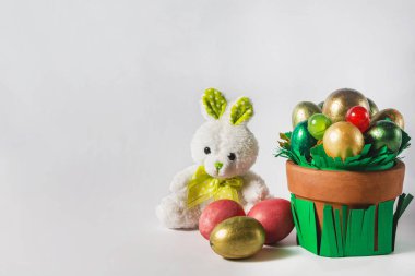 Paskalya tatili konsepti. Bir tencere renkli yumurta, şeker ve oyuncak tavşan..