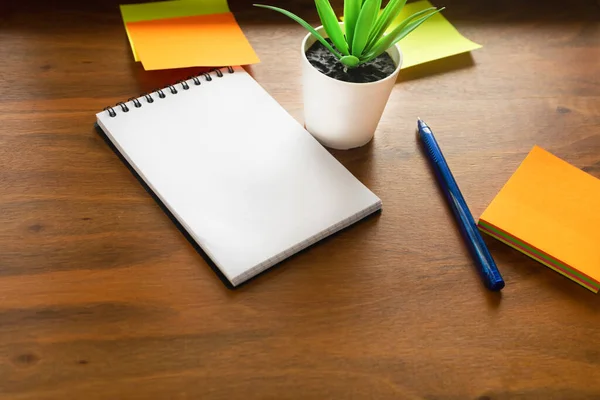 Workplace concept. The flower, notebook and stickers are located on the surface of the writing table.