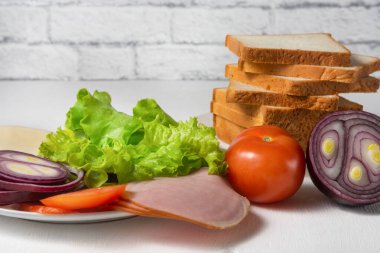 Taze salata, domates, jambon, peynir ve ekmek sandviçler için hazırlanır. Fast food konsepti.