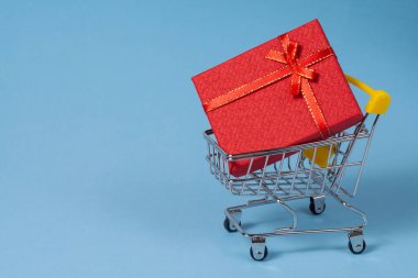 Noel ya da doğum günü için kırmızı bir kutuda bir hediye süpermarket arabasındadır. Tatil için hediye alma kavramı. Hediyelerde indirim.
