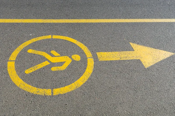 Yellow sign denoting pedestrian space on the road. Walking road in the park. Pedestrian figurine sign painted in yellow paint on black asphalt sidewalk.