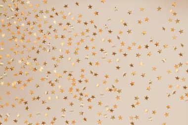 Yıldızların altın parıltılı konfetileri soyut, bulanık bej arka planda izole edilmiş. Bayram geçmişi. Kutlama konsepti. Düşen sihirli altın parçacıkları. Davetiye maketi. Üst manzara, düz uzanma