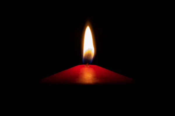 Isolated red candle with flame in front of dark background