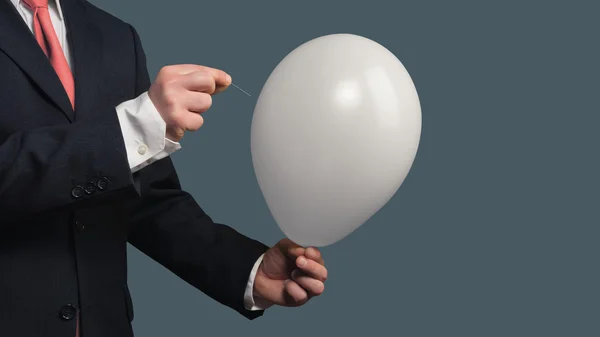 Человек в костюме позволяет воздушному шару лопнуть иглой — стоковое фото