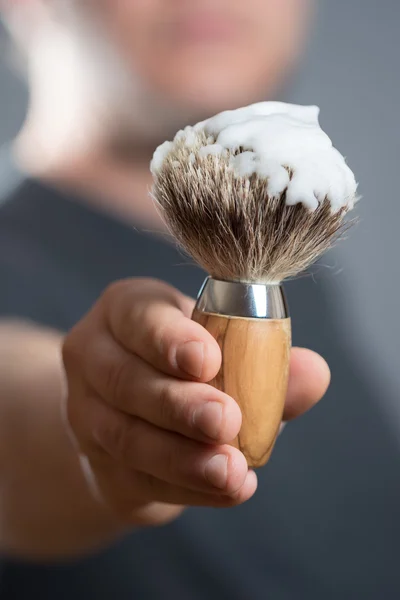 El hombre sostiene un cepillo de afeitar en la mano — Foto de Stock