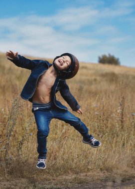 Motosiklet kasklı küçük çocuk zıplıyor ve sokakta eğleniyor.