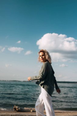 Kadın kumsalda yürüyor.