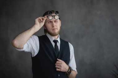 Beyaz gömlekli ve büyük siyah gözlüklü bir adam kameraya bakar.