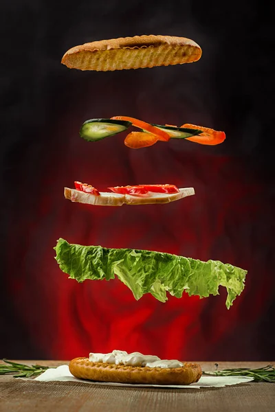 Tavuk, salatalık ve salatalıklı sandviç malzemeleri havada asılı.