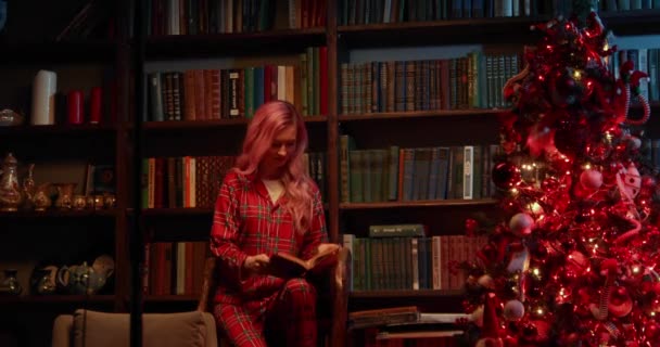 Kvinna Röd Pyjamas Och Med Rosa Hår Läser Bok Biblioteket — Stockvideo