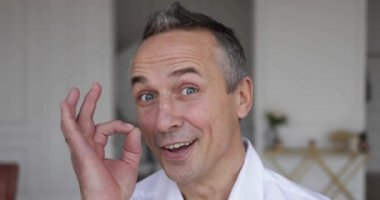 İki parmağını havaya kaldıran yetişkin bir adamın yüzü.