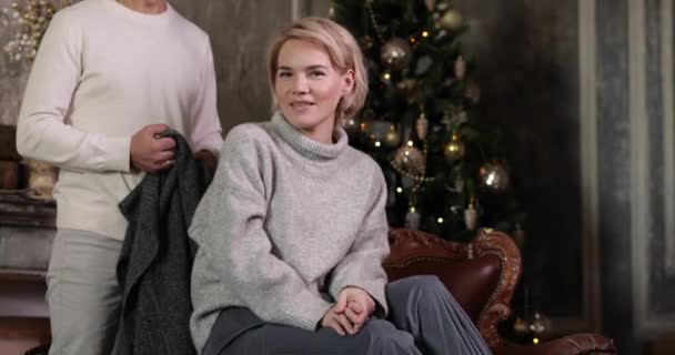 大人の男はクリスマスツリーの部屋にグレーの暖かい毛布を持つ女性を飾る — ストック動画