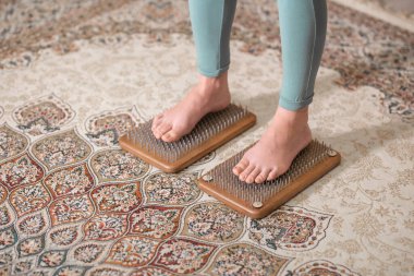 Yogi kadın çivilerin üzerinde duruyor, bacakları kapalı.