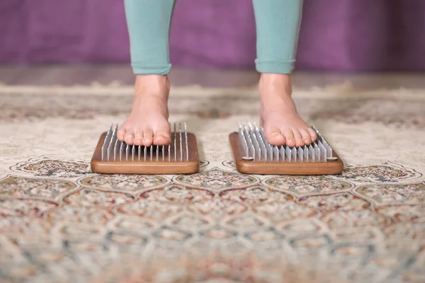 Yogi kadın çivilerin üzerinde duruyor, bacakları kapalı.