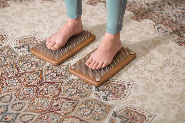 Yogi kadın çivilerin üzerinde duruyor, bacakları kapalı.