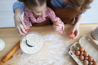 Anne ve kızı mutfakta un ve yumurta pişiriyorlar.