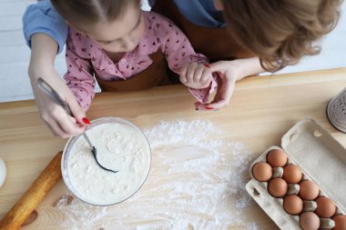 Anne ve kızı mutfakta un ve yumurta pişiriyorlar.