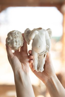 Kırık bir melek figürü tutan bir kadın - vücut ve kafa